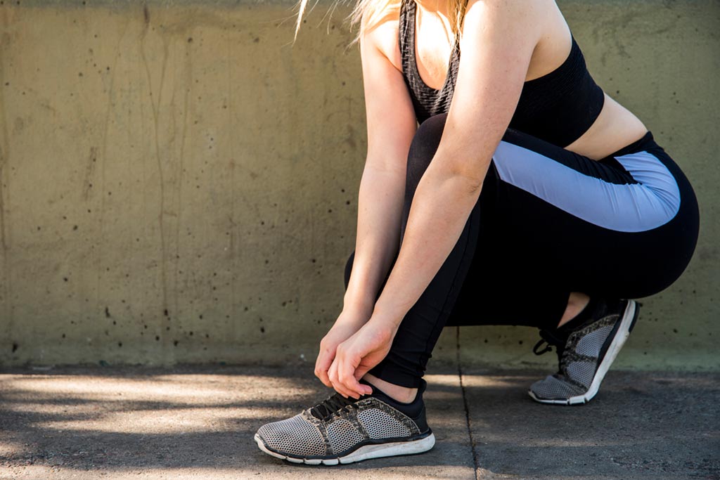 Mujer joven atandose los cordones de sus zapatillas deportivas